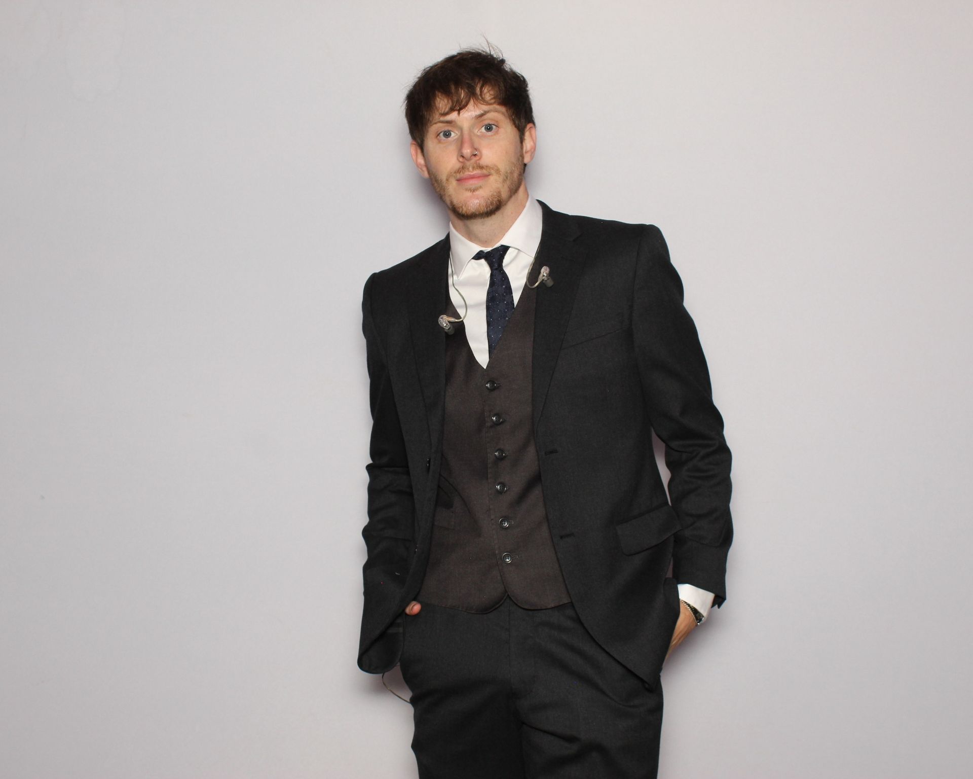 A man in a suit and tie is standing with his hands in his pockets.