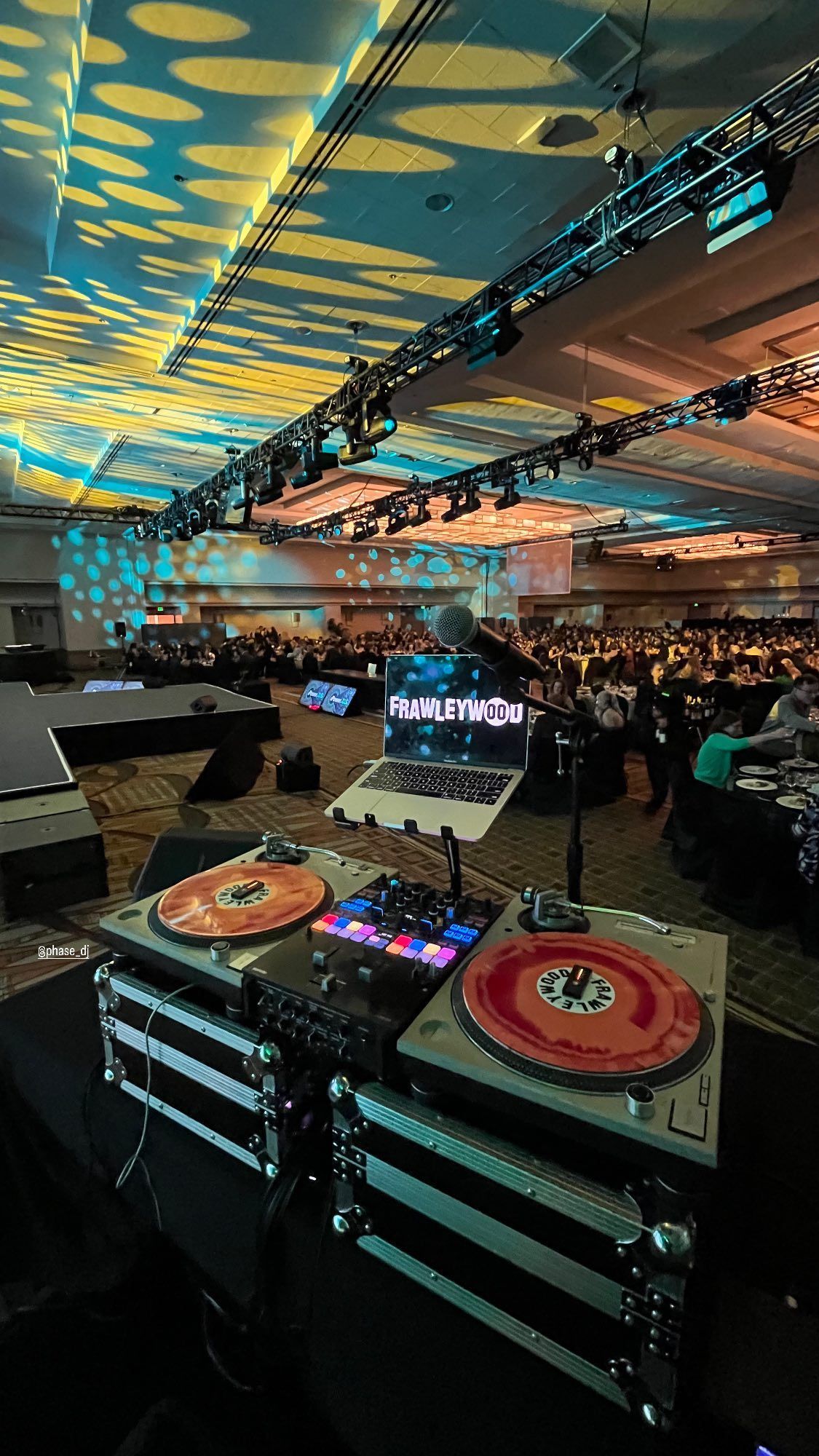 A dj is playing music in a large room.