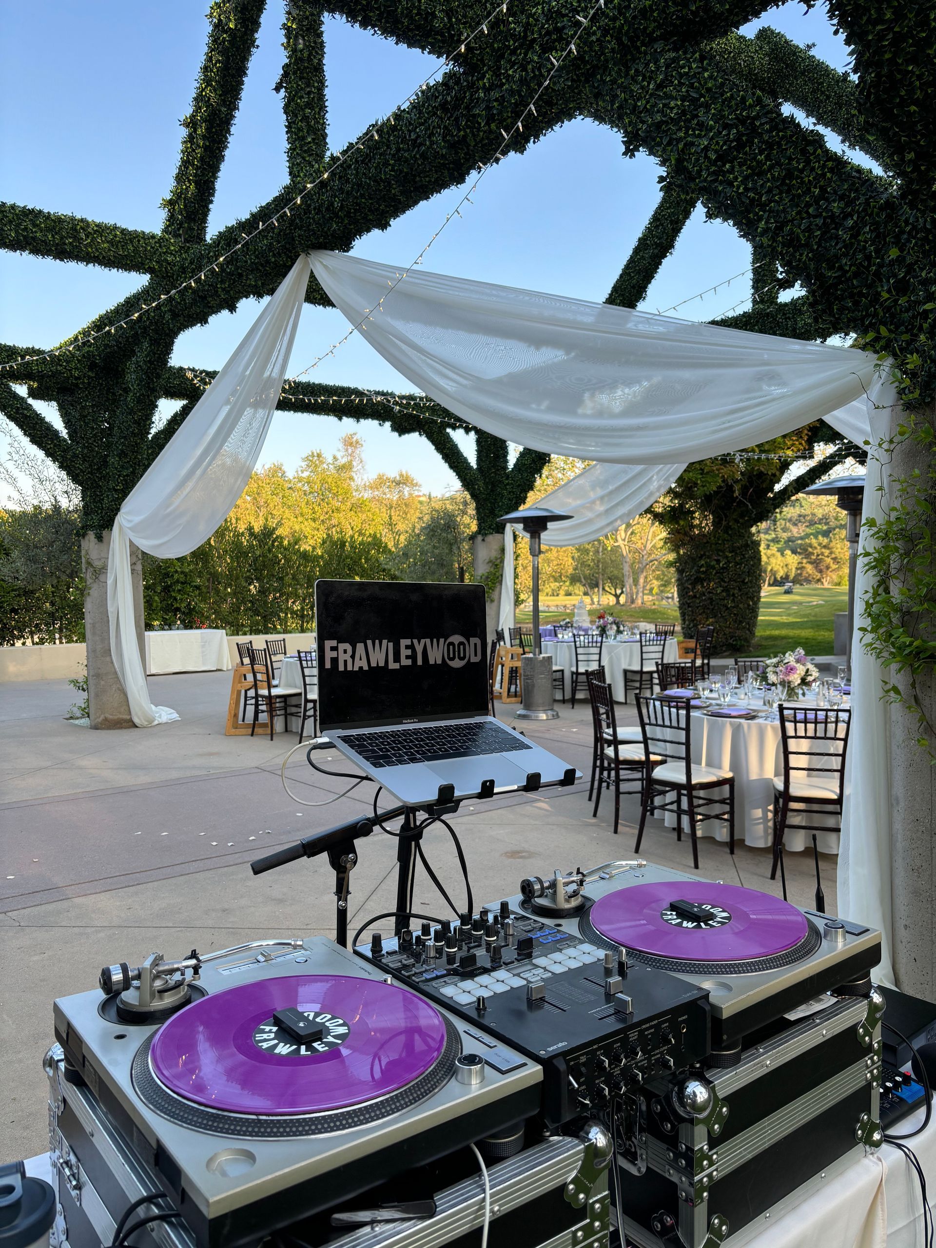 A dj is playing music at a wedding reception under a canopy.