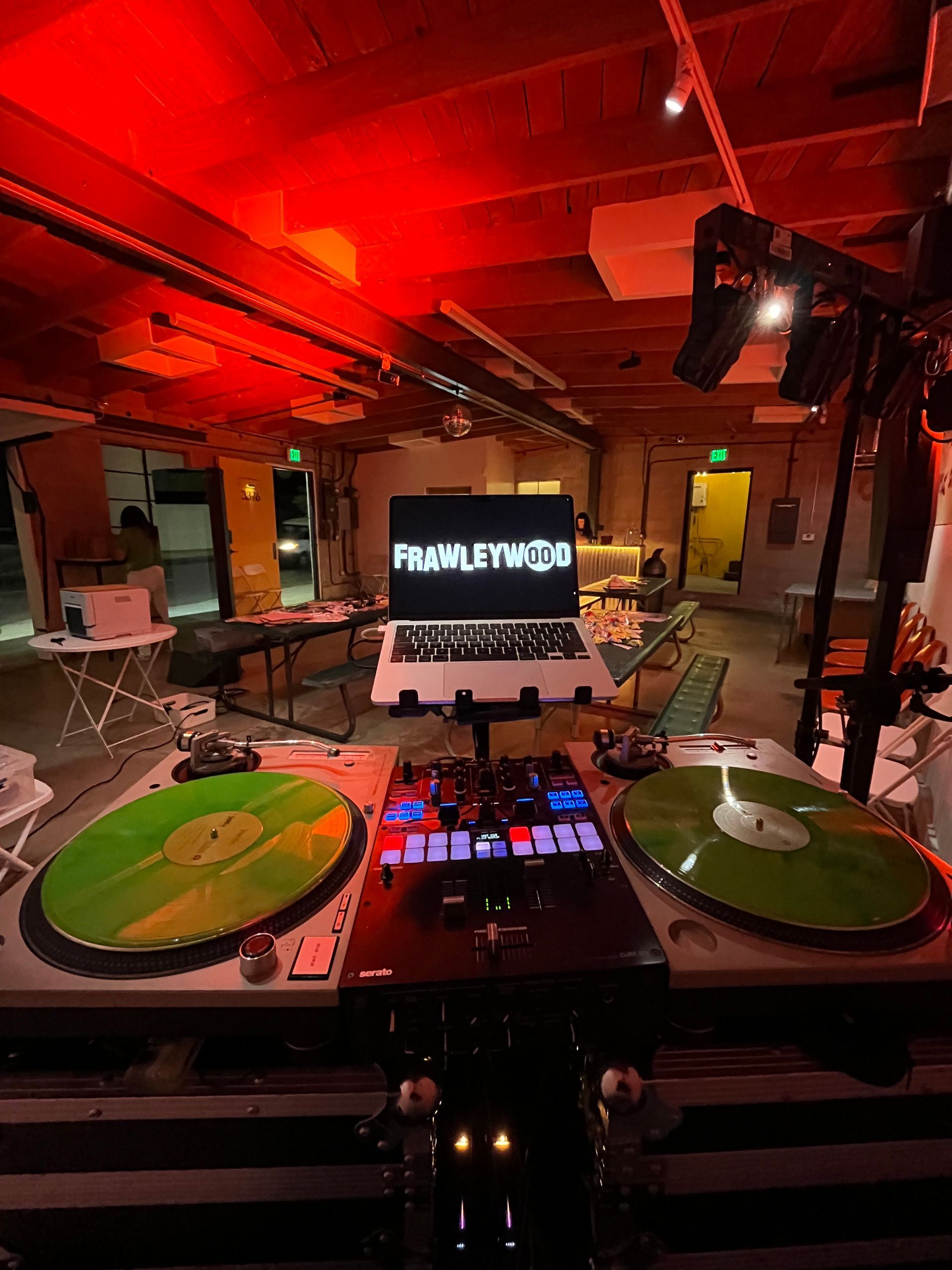A dj booth with two turntables and a laptop.