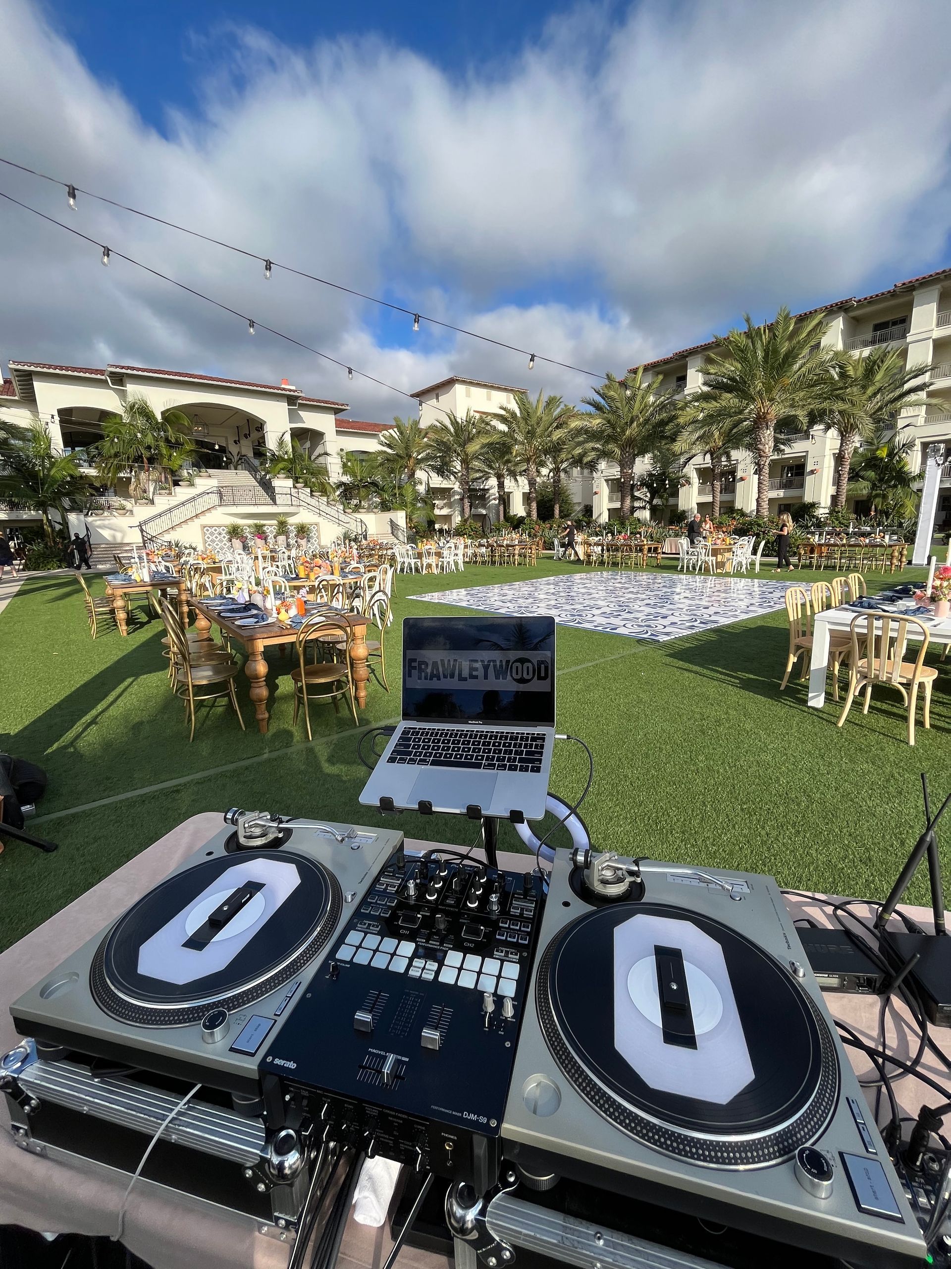 A dj is playing music at a wedding reception in a lush green field.