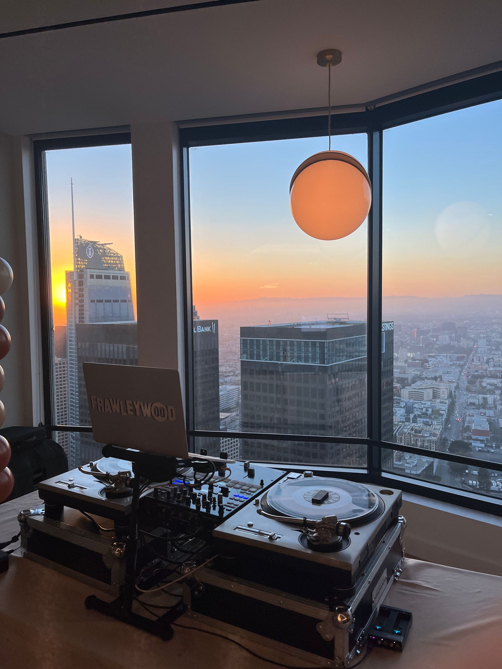 A room with a view of a city and a laptop on a table.