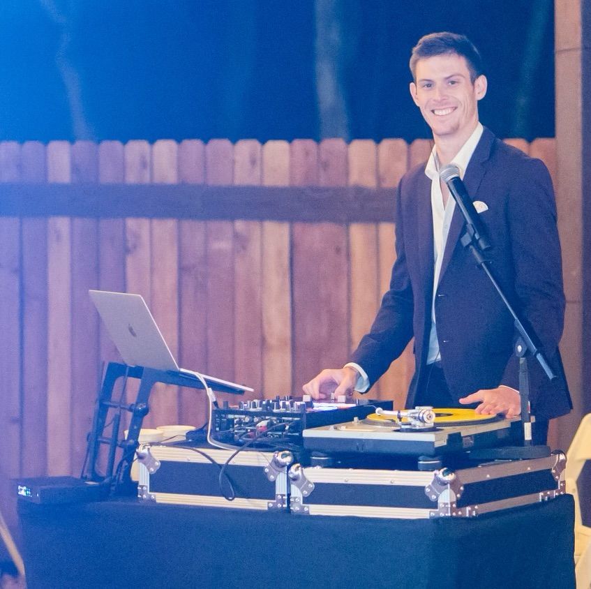 A man in a suit is standing in front of a laptop and a microphone