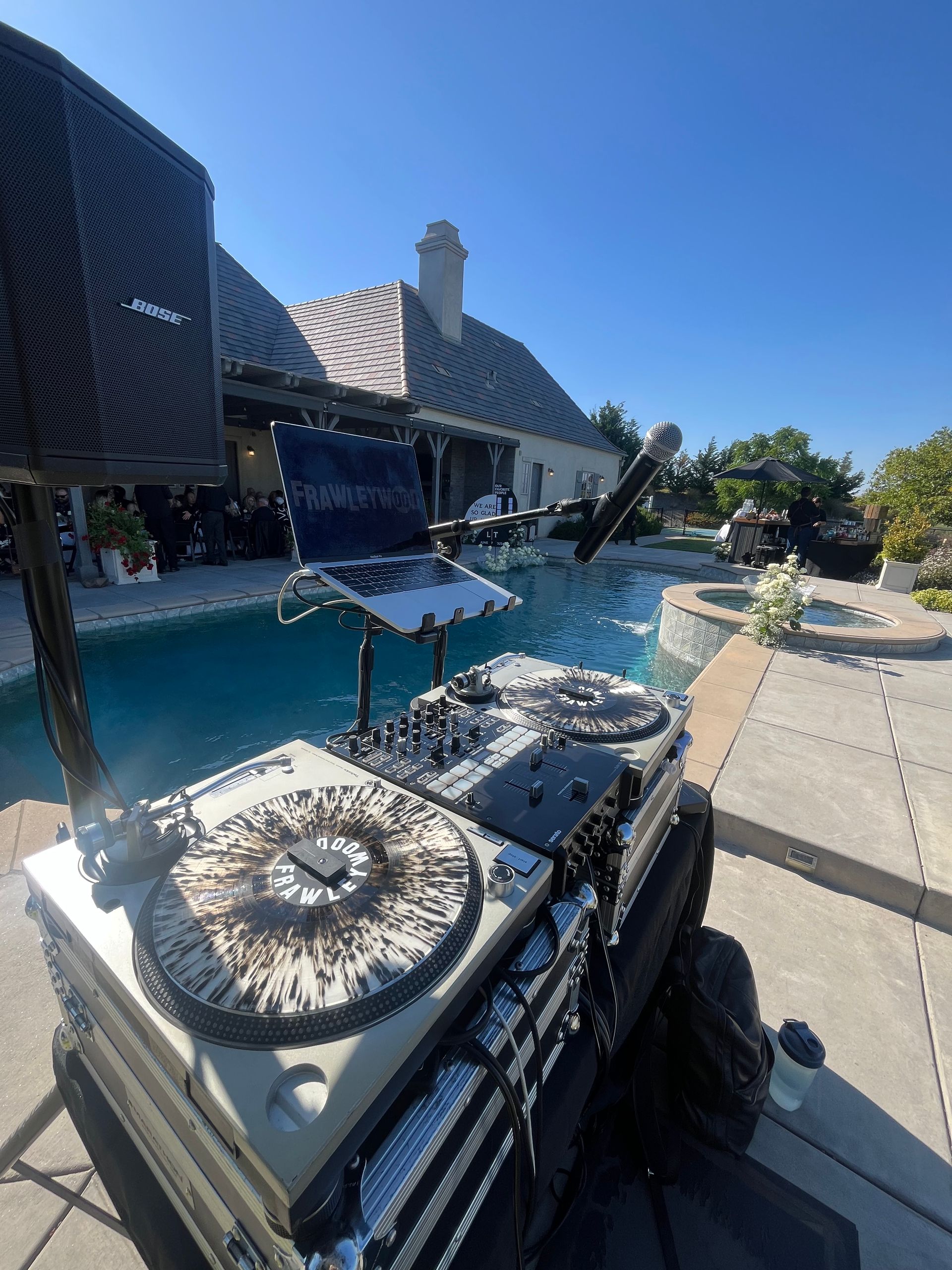 A dj set is sitting on a patio next to a pool.