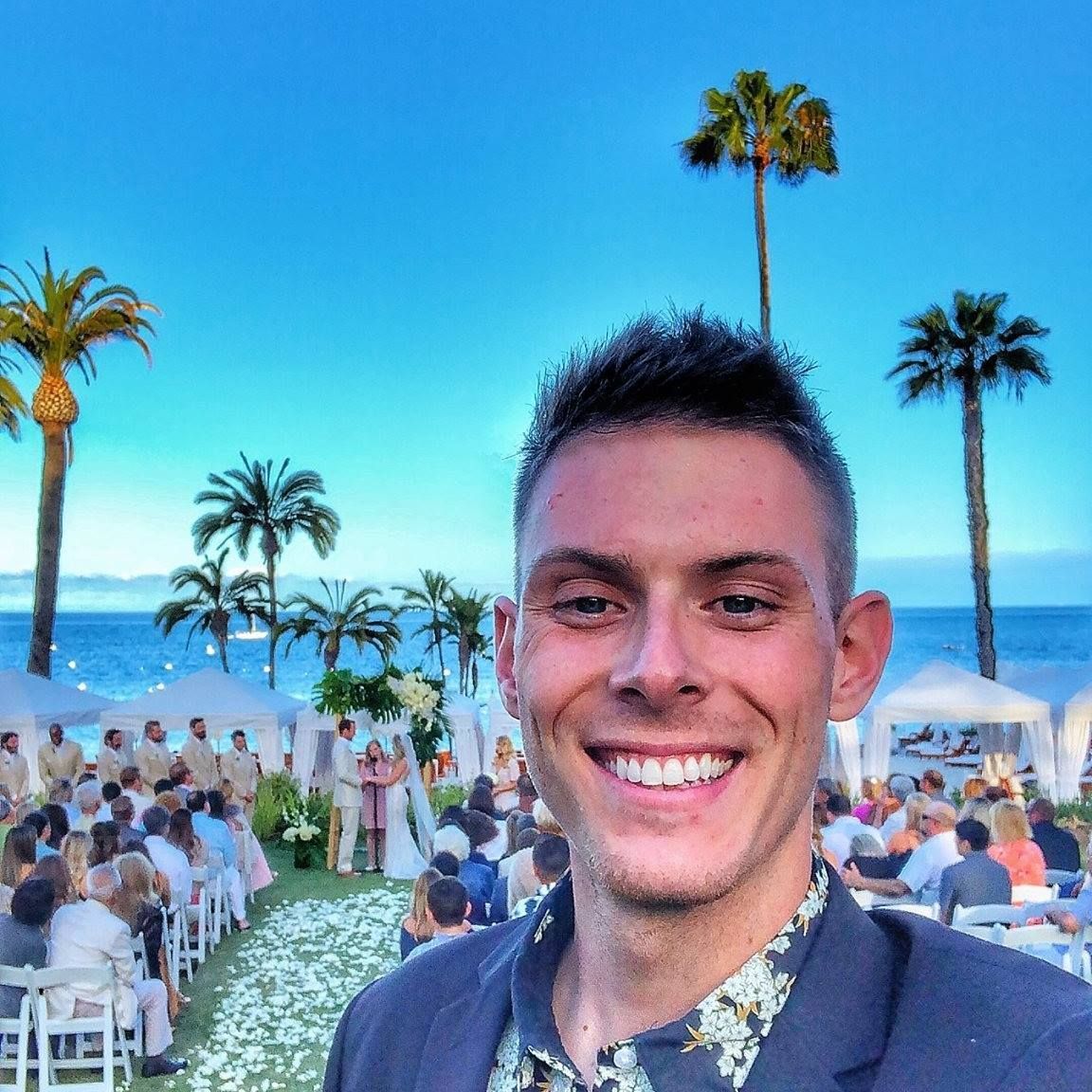 A man in a suit is smiling in front of a crowd at a wedding