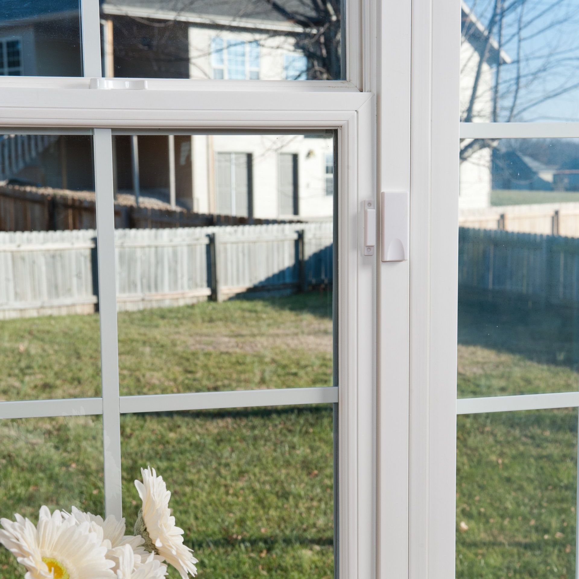 A window with a reflection of a house and a fence in it