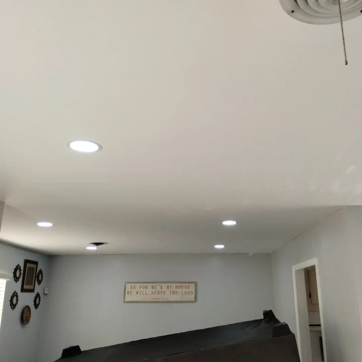 Ceiling with recessed lights, gray walls, and a glimpse of furniture and decor.