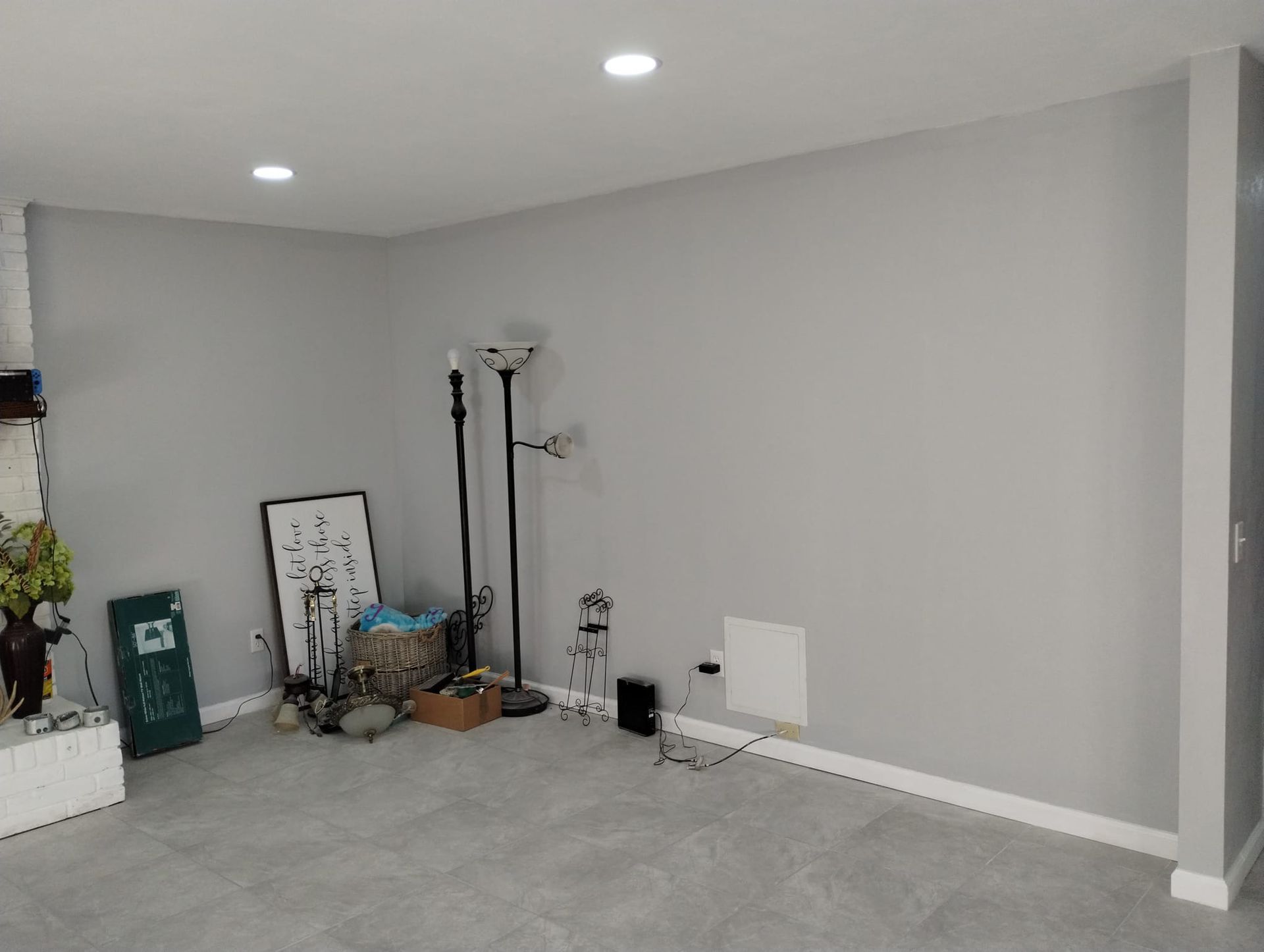 Empty room with gray walls, recessed lights, and clutter along the left wall.