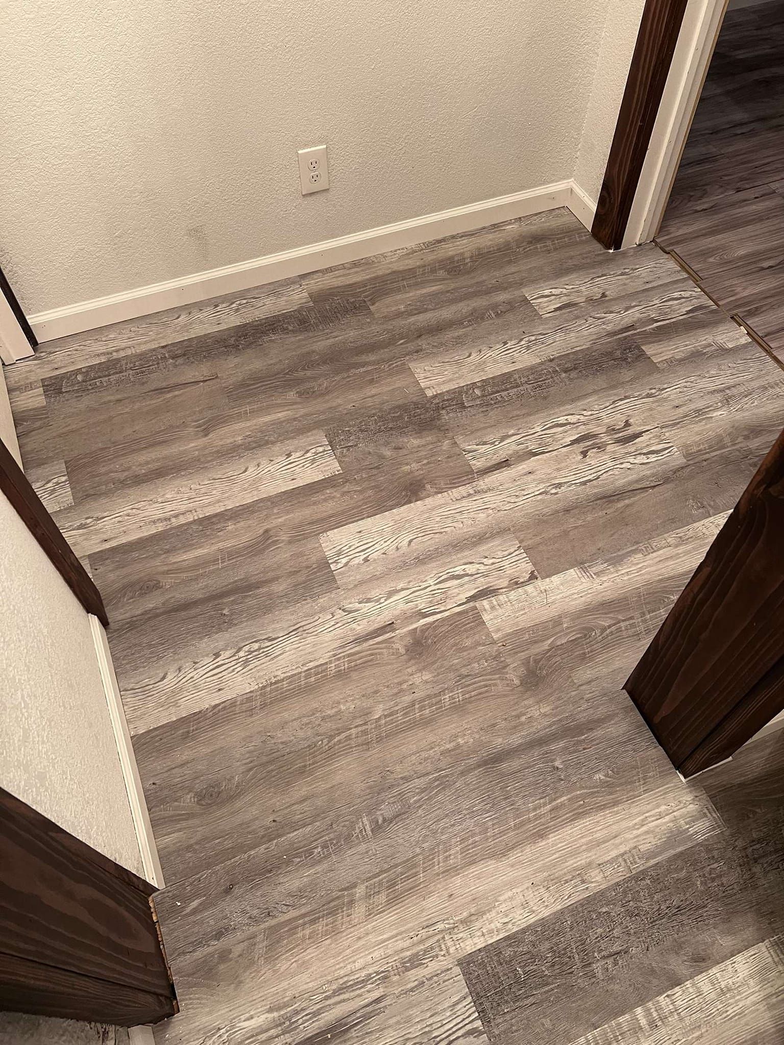 Hallway with gray and white plank flooring and white walls.