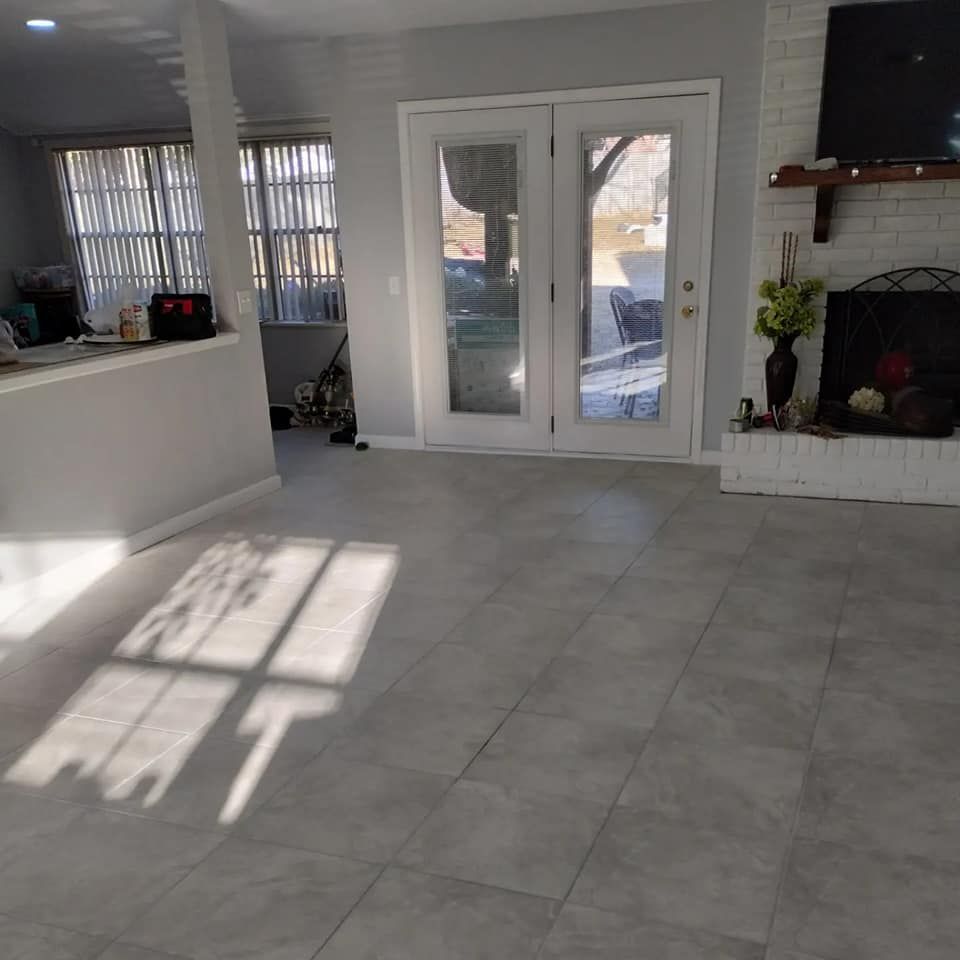 Grey-tiled living room with a white fireplace, double doors, and a partial view of the outdoors.