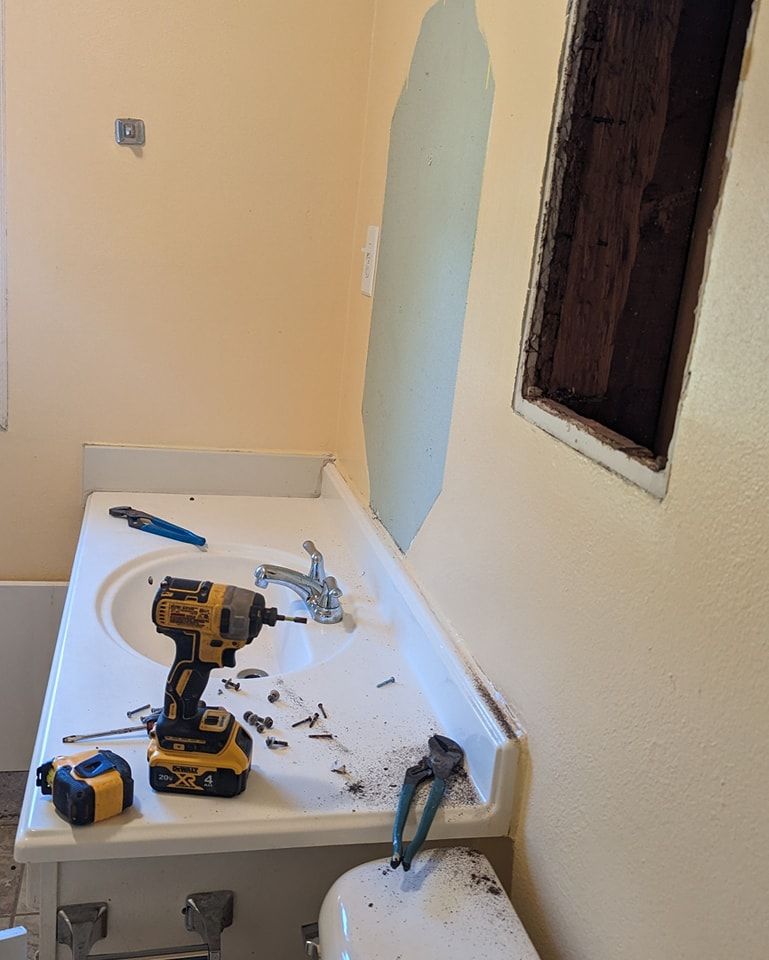 Bathroom under construction: sink with tools, exposed wall.