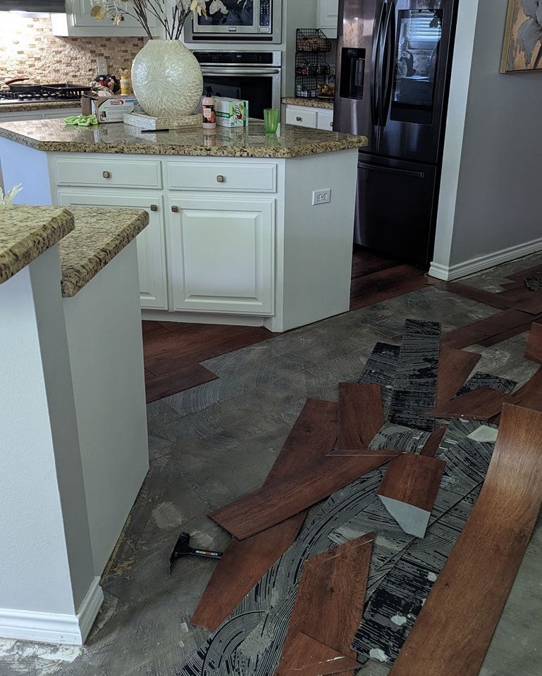 Kitchen with island, partially installed wood flooring, and exposed subfloor.