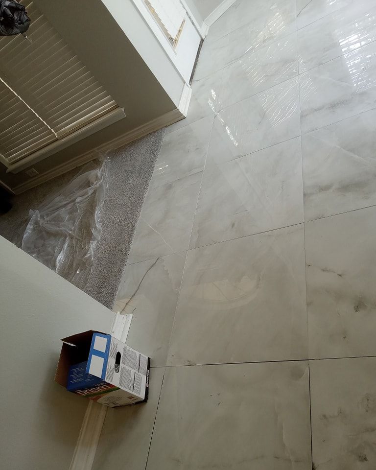 New tile floor installation in progress, near a wall and open door. Brown cardboard box.