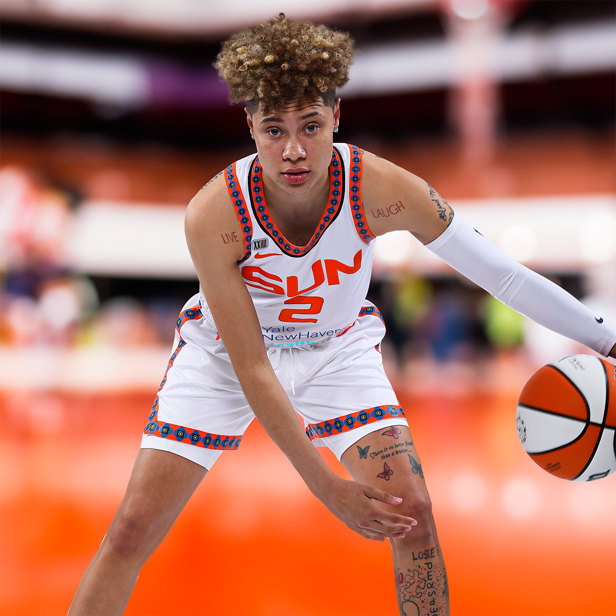 A woman in a sun jersey is holding a basketball