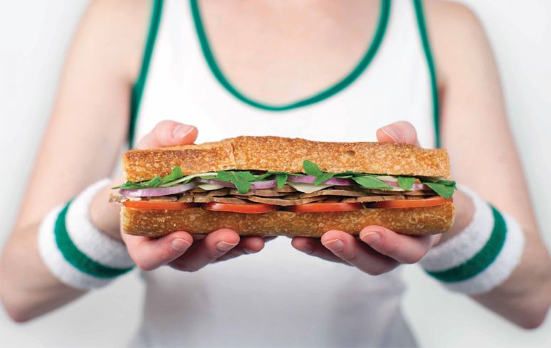 A woman is holding a sub sandwich in her hands