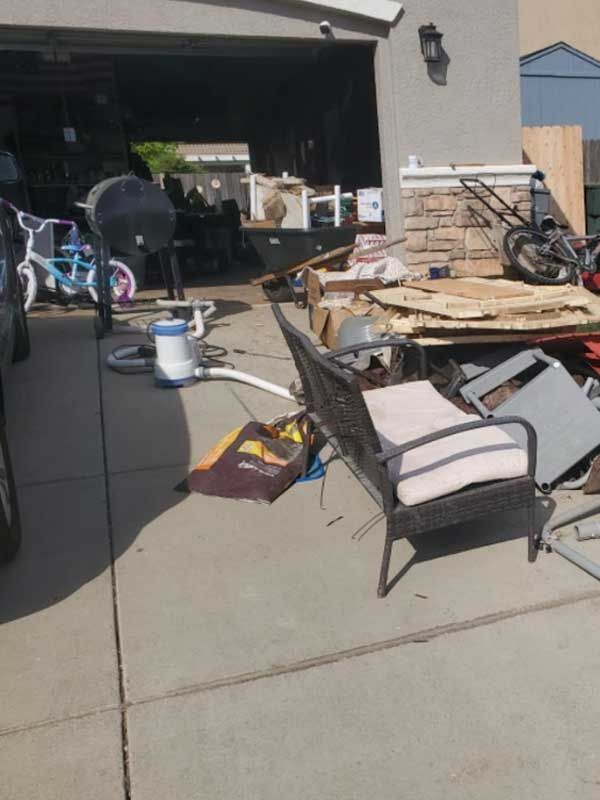 a wicker chair sits in front of a garage full of junk
