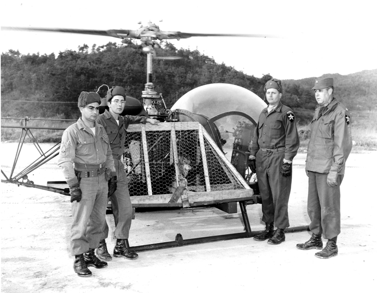 A group of soldiers standing in front of a helicopter