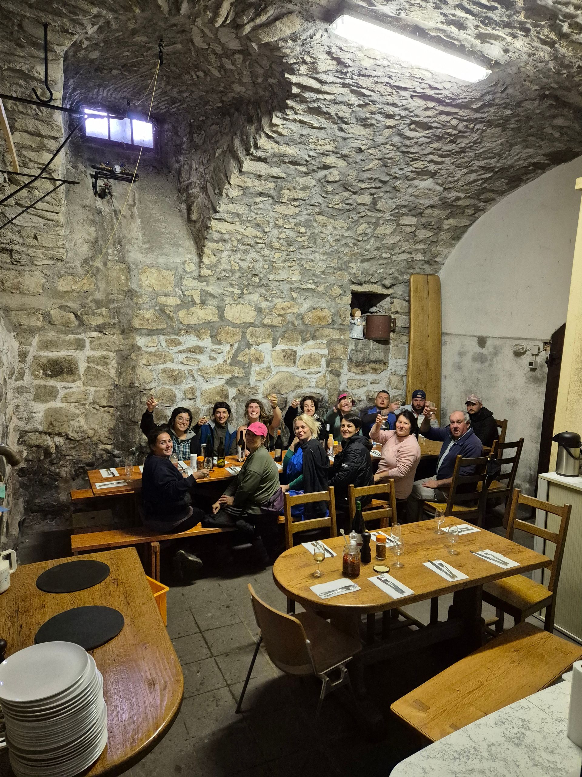 Un groupe de personnes sont assises à des tables dans une pièce en pierre.