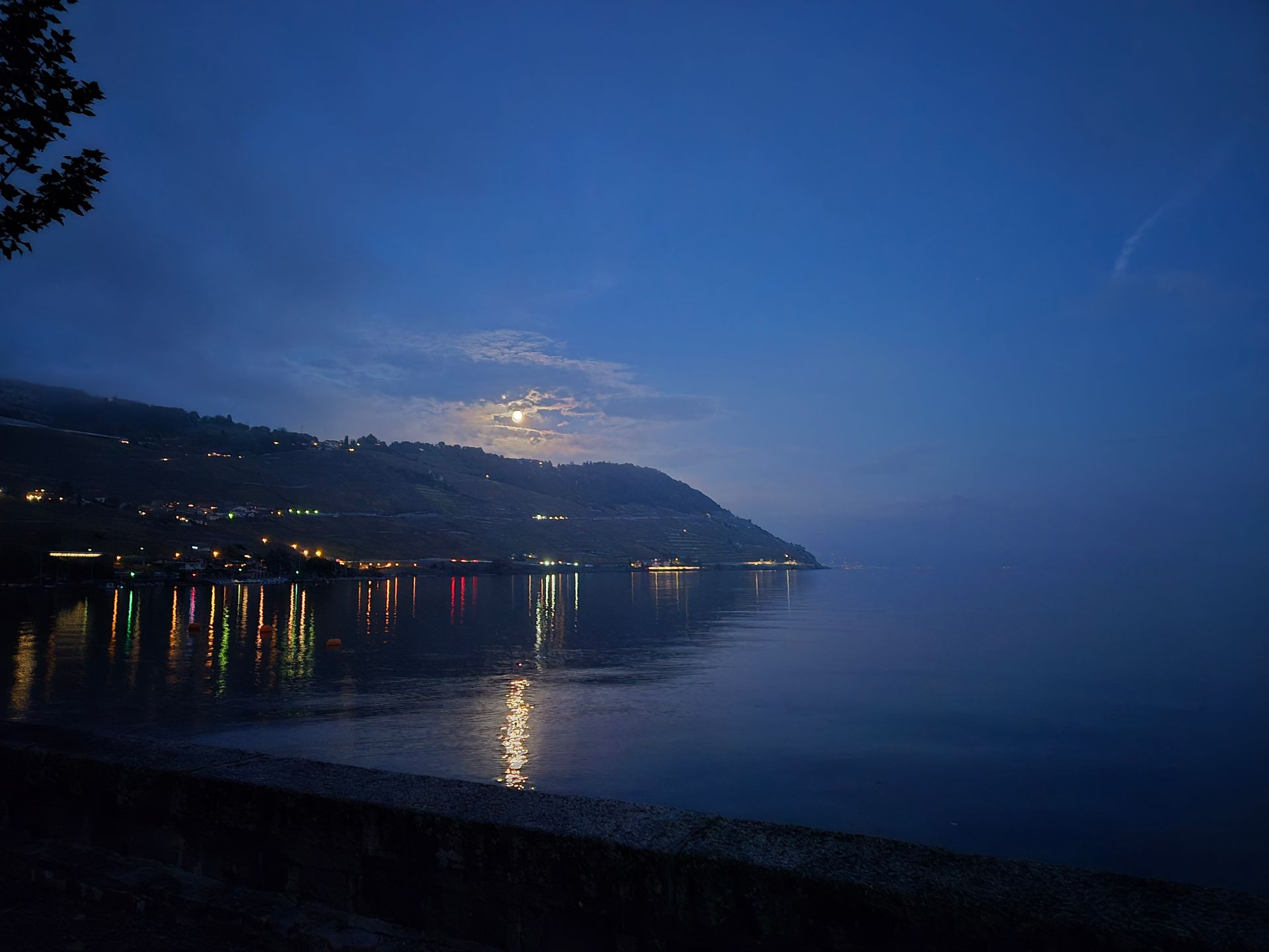 Une pleine lune se lève sur un lac la nuit