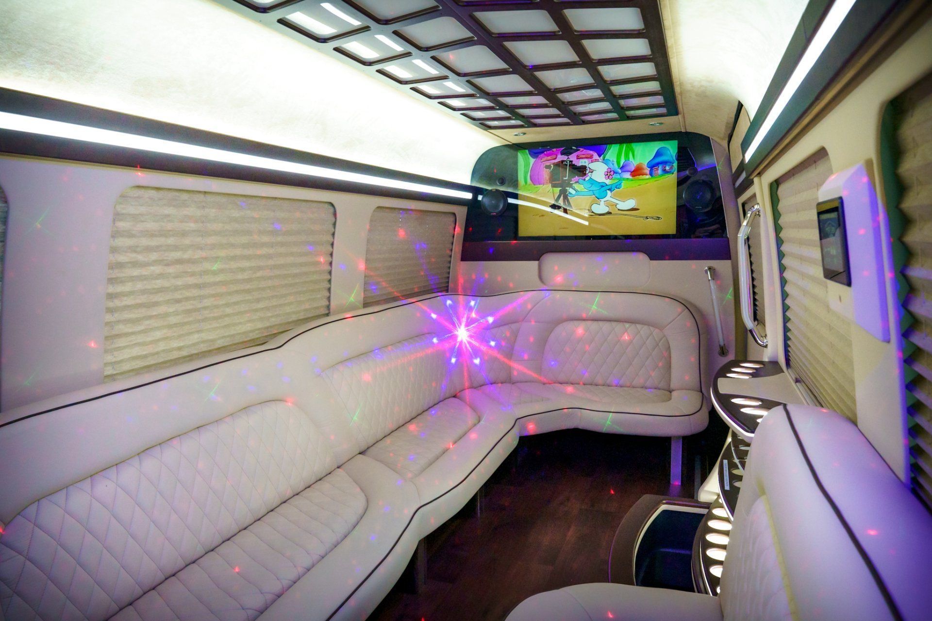 The inside of a limousine with a tv on the ceiling