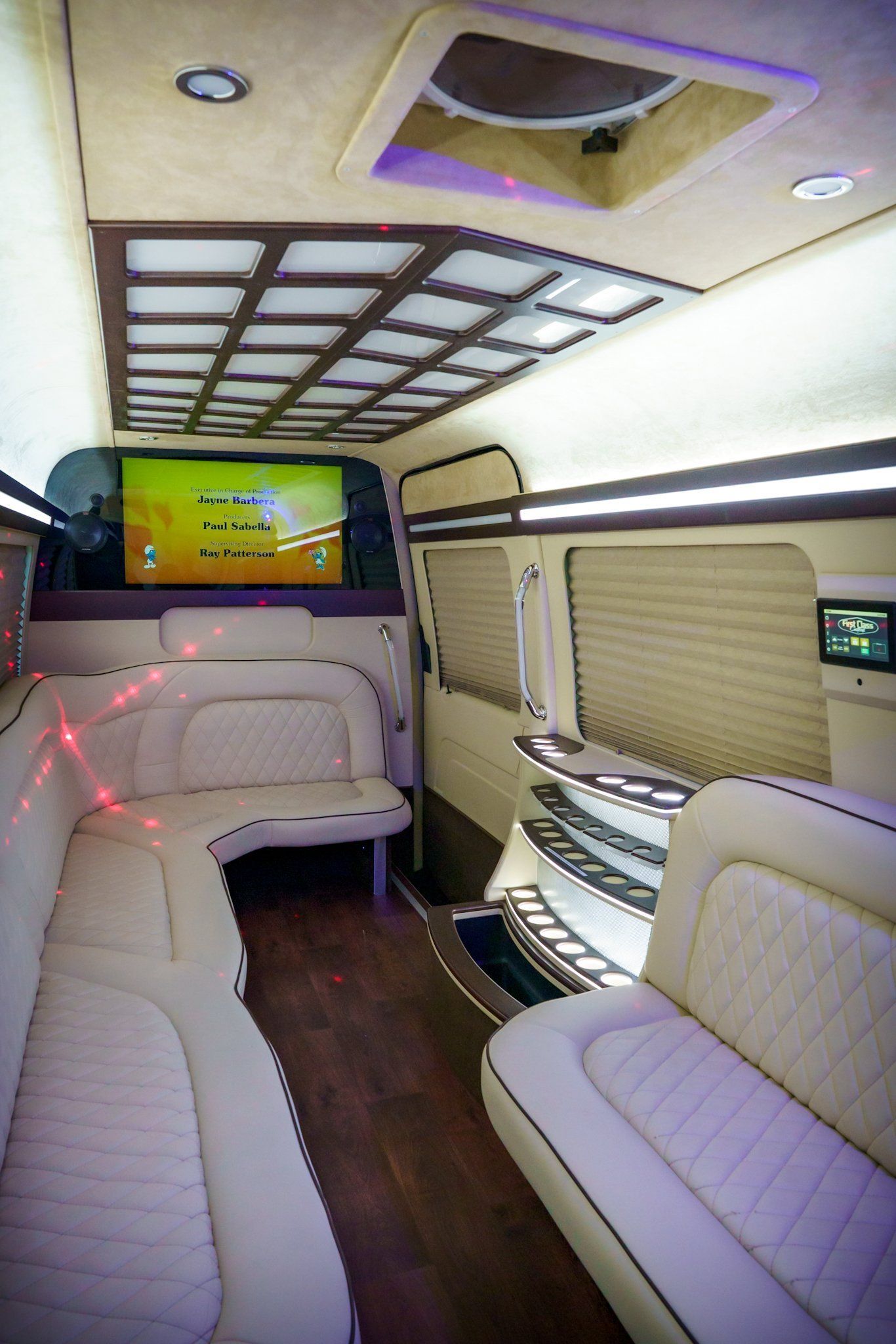 The inside of a limousine with a couch and a television.