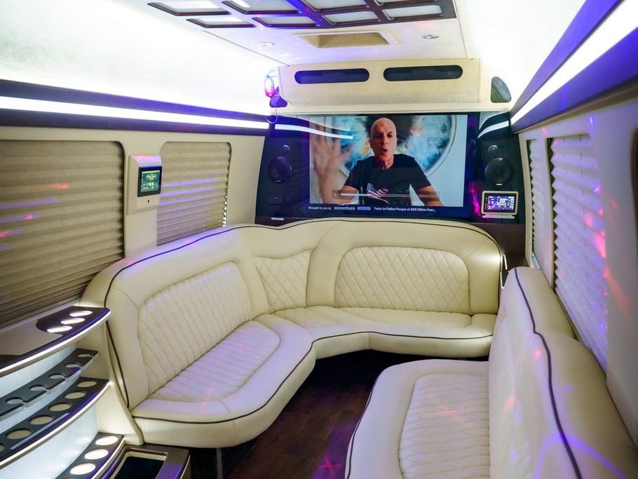 The inside of a limousine with a couch and a television