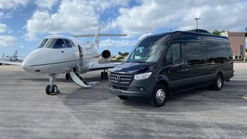 A van is parked next to a private jet on a runway.