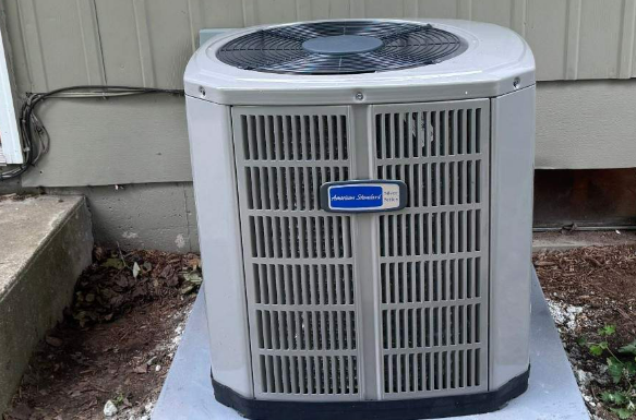 A white American Standard air conditioning unit outside a building.