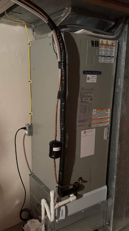 A furnace in a basement. Wires run along the side.