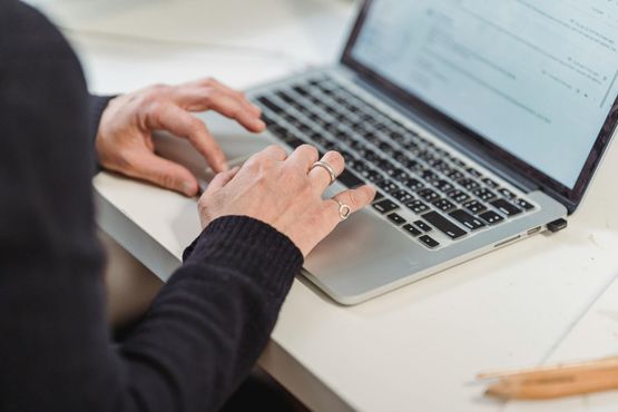 Hands typing on a silver laptop at a desk with a blurred document on screen