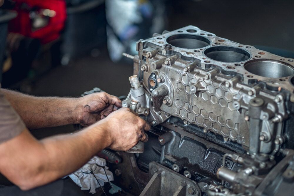 A Man Is Working On A Car Engine In A Garage — P & M Performance & Mechanical In Bungalow, QLD