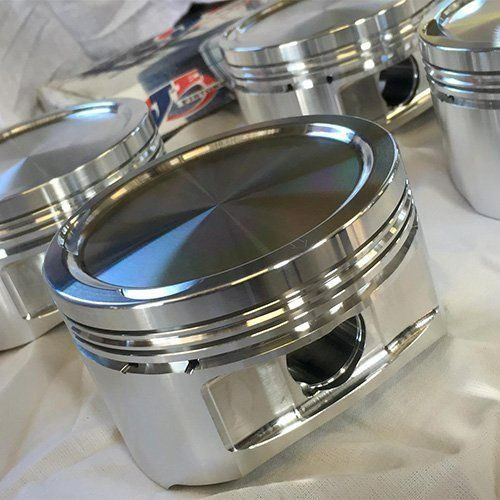 A Group Of Pistons Are Sitting On Top Of Each Other On A Table — P & M Performance & Mechanical In Bungalow, QLD