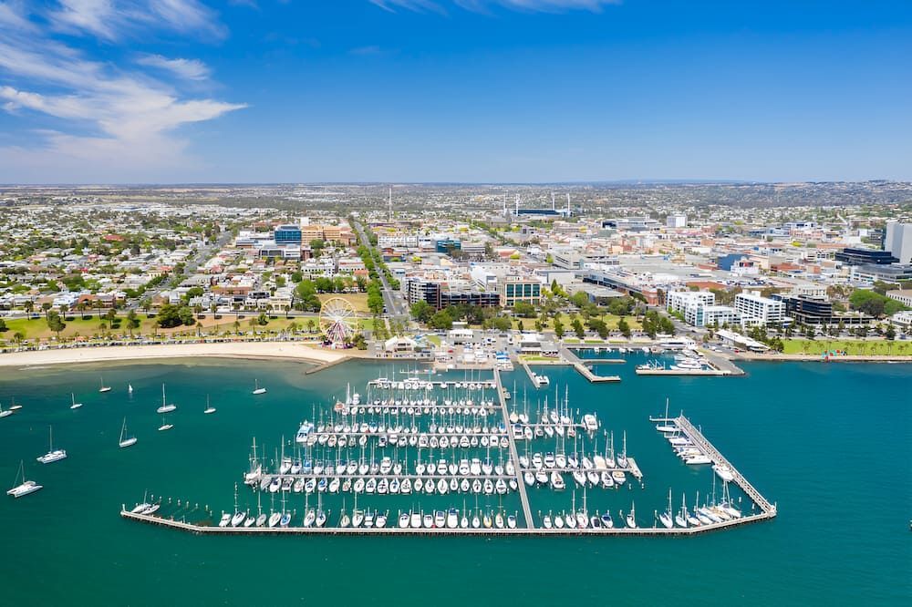 An Aerial View Of A Marina With Boats Docked In The Water And A City — Justin Drew Plumbing in North Geelong, VIC