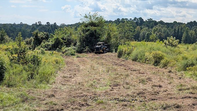 A tractor is driving down a dirt road in a field.