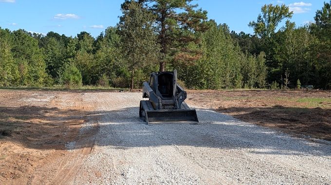 A bulldozer is driving down a dirt road in a field.
