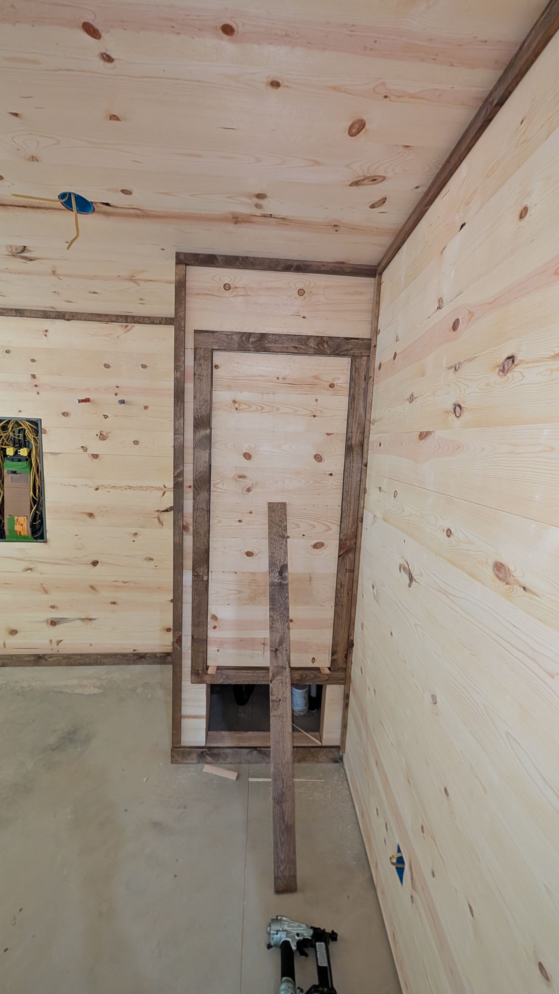 Interior of a room under construction with wood paneling on the walls and ceiling.