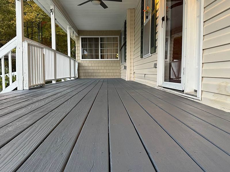 A large porch with a ceiling fan on it