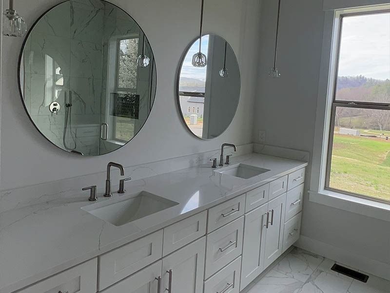 A bathroom with two sinks and two round mirrors.