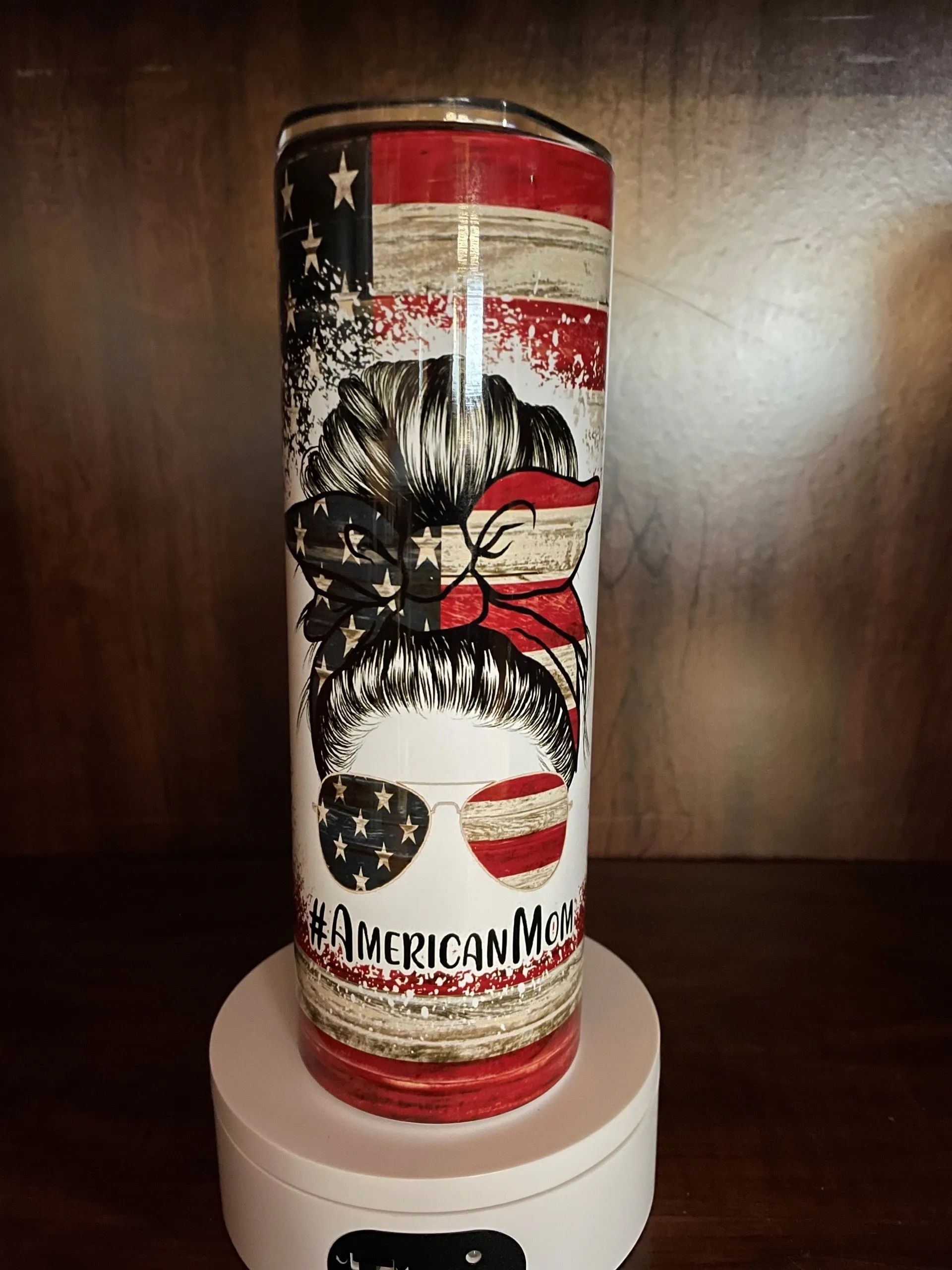 A stainless steel tumbler with an american flag on it is sitting on a table.