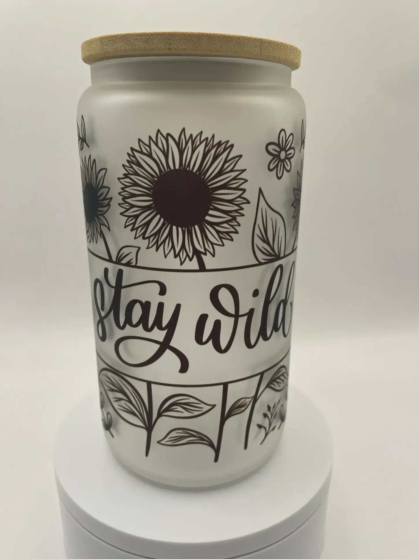 A white jar with a wooden lid that says stay wild