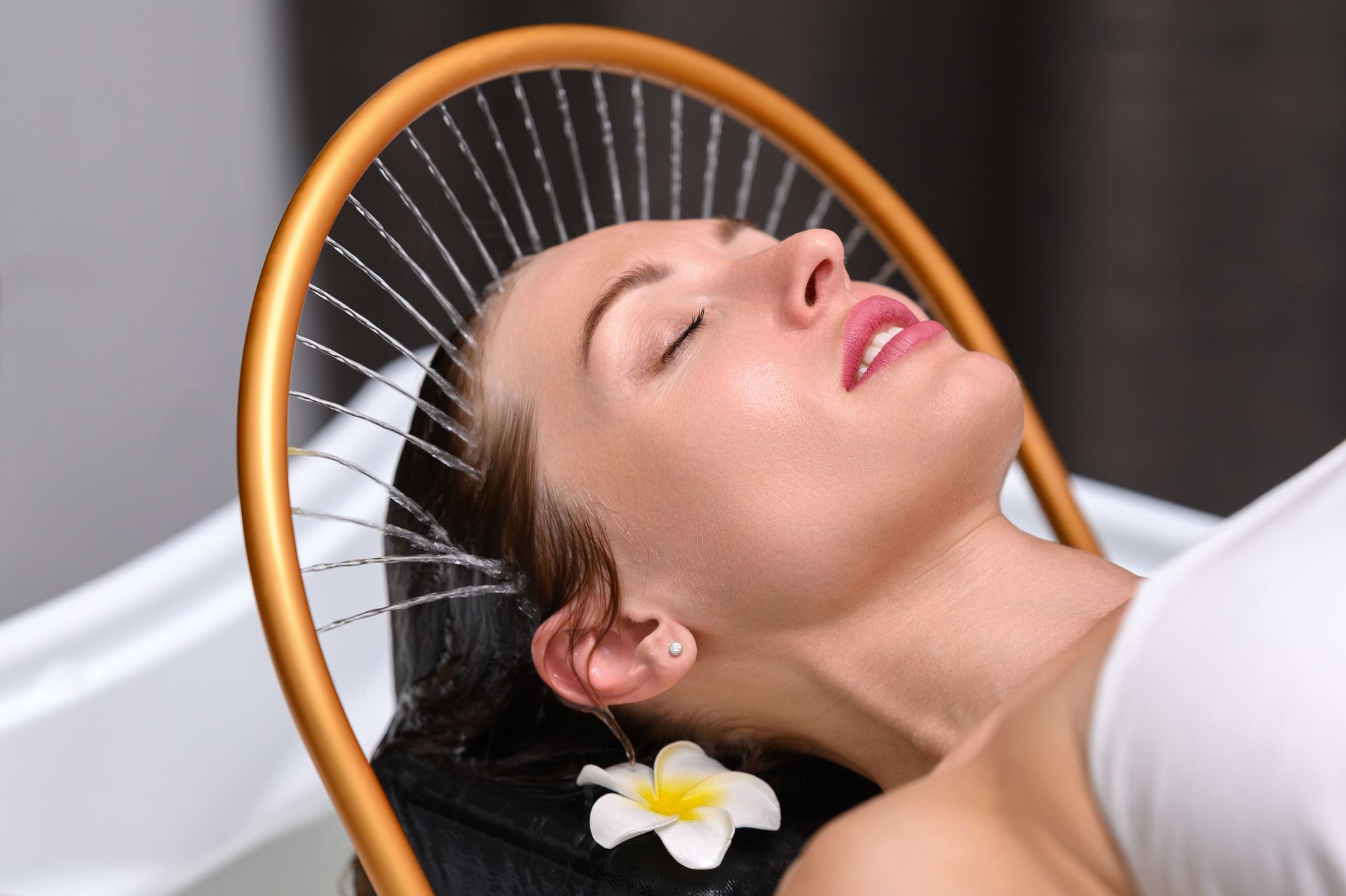 Eine Frau bekommt in einem Spa eine Kopfmassage, im Hintergrund leuchten Kerzen.