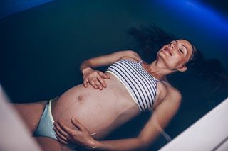 Eine Frau schwimmt mit geschlossenen Augen in einer Badewanne.