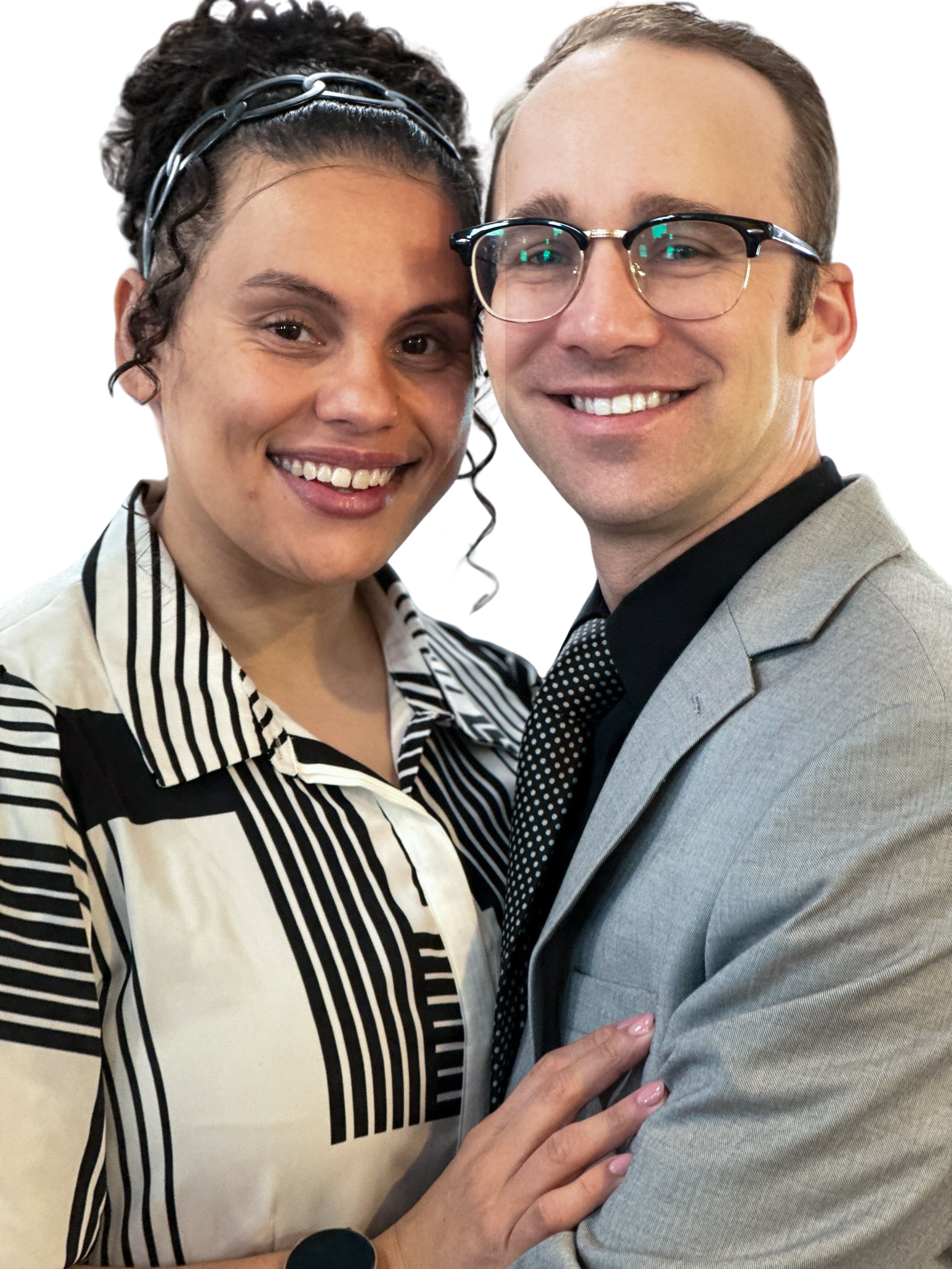 Couple smiling, embracing. Woman with curly hair, striped shirt. Man with glasses, gray suit.