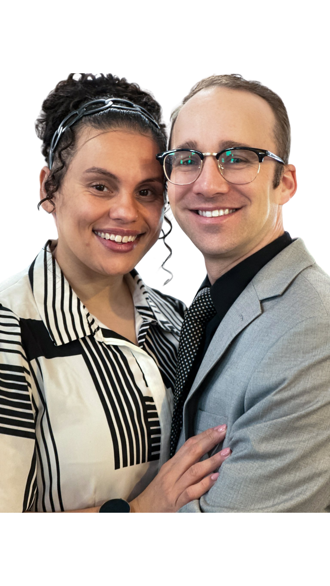 Couple smiling, the woman wearing a black and white striped shirt, the man in a suit with glasses.