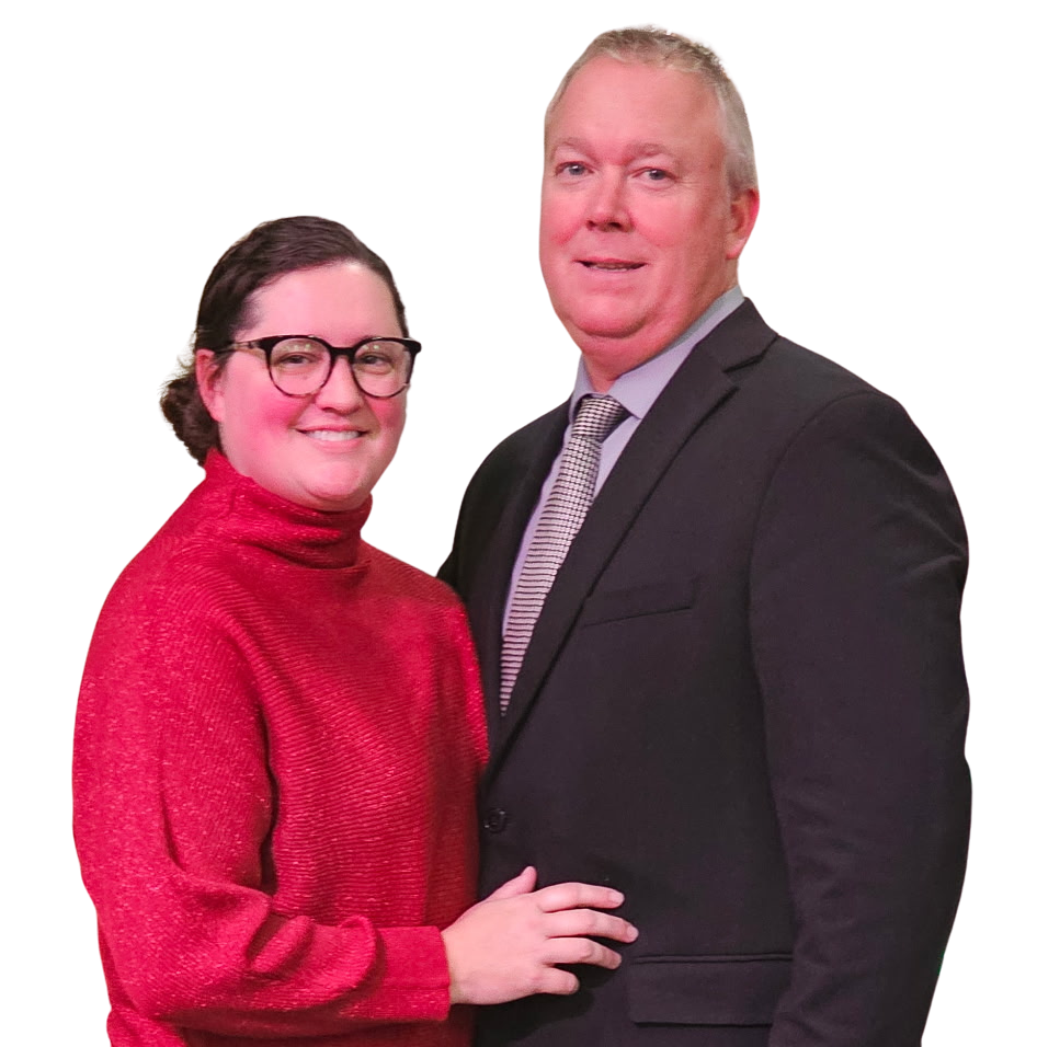 Woman in red sweater and man in suit smiling, standing close together.