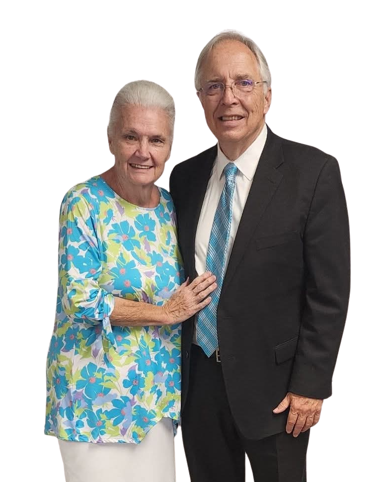 Man and woman posing together. Man in suit, woman in striped top. They are smiling.