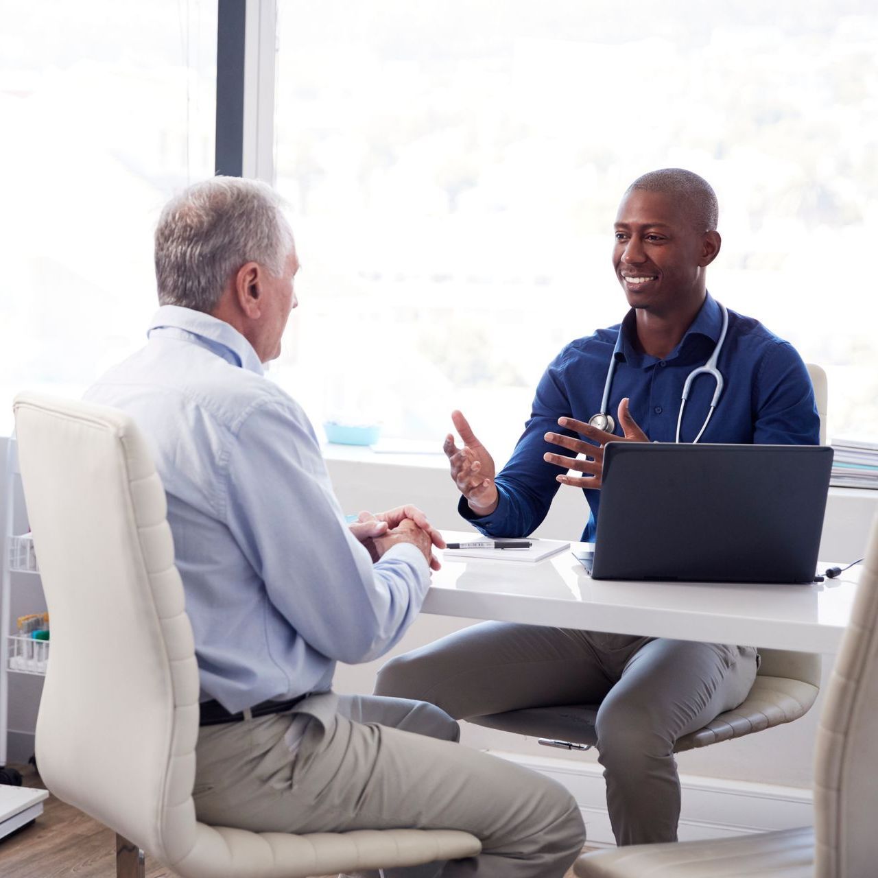 An older woman is sitting at a desk using a laptop computer.