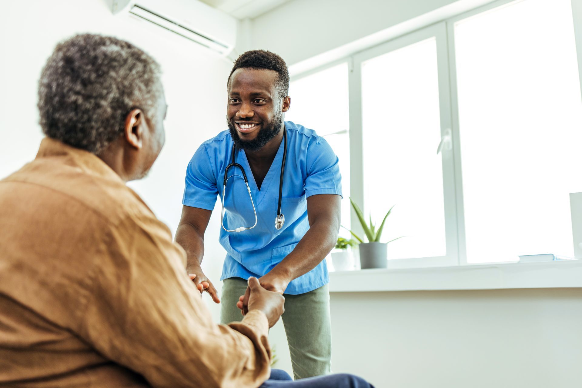 A nurse is shaking hands with an elderly woman in a hospital room.