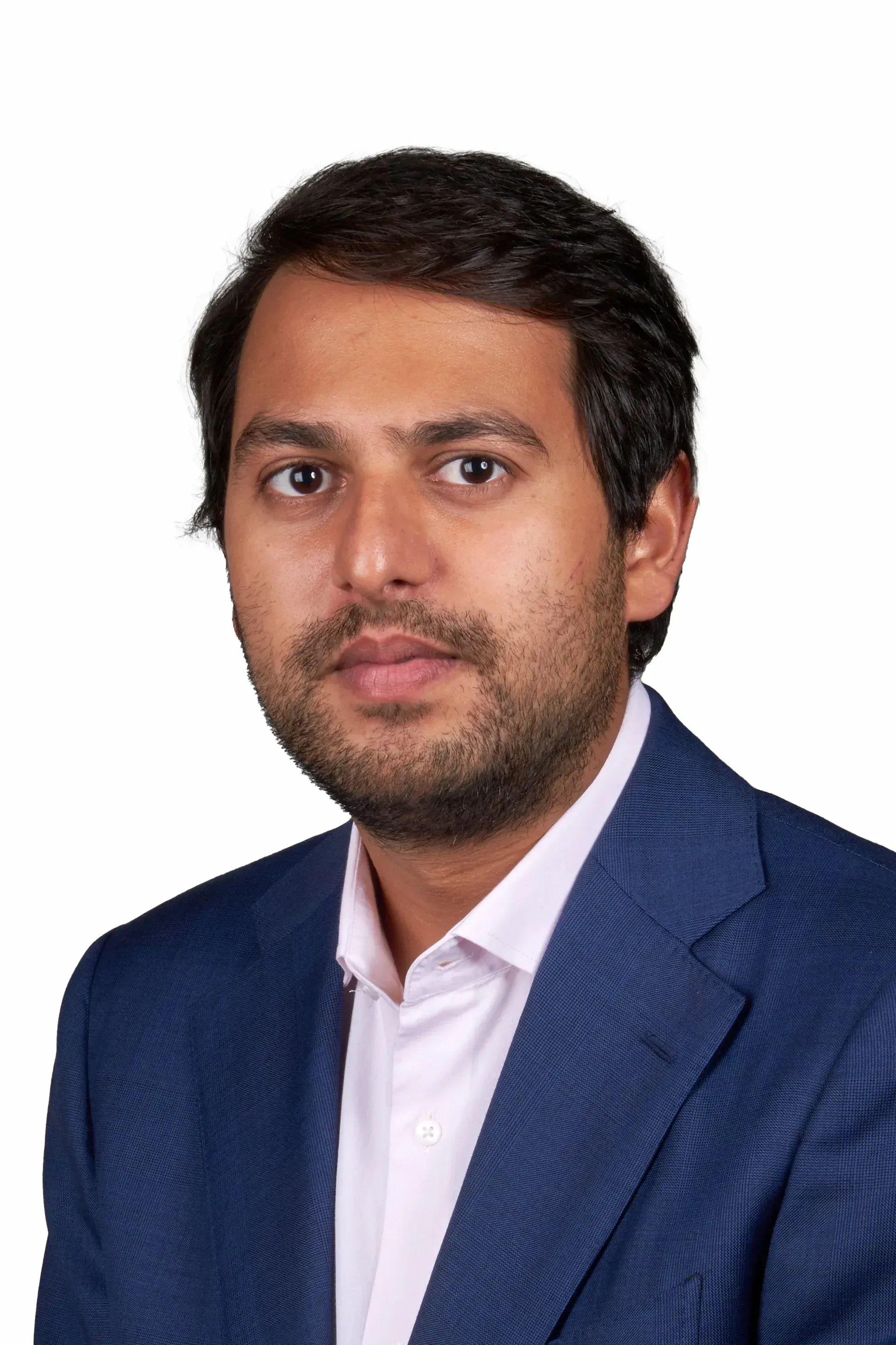 A man with a beard is wearing a blue suit and a pink shirt.