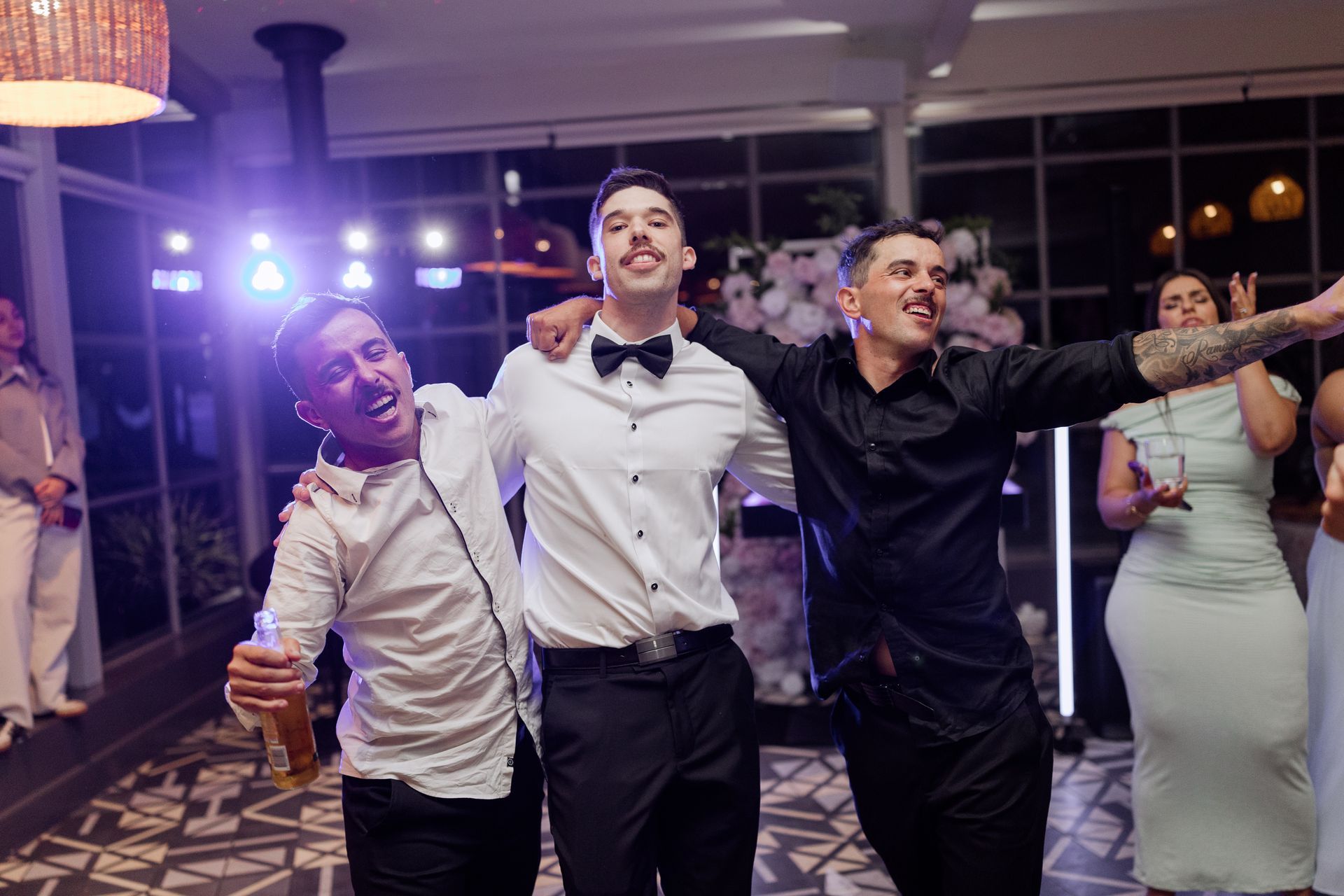 Three men are standing next to each other on a dance floor.